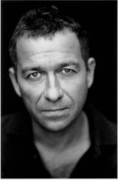Sean Pertwee, nekompromisný, no nakoniec zavraždený dozorca chlapčenskej pospolitosti na ostrove.